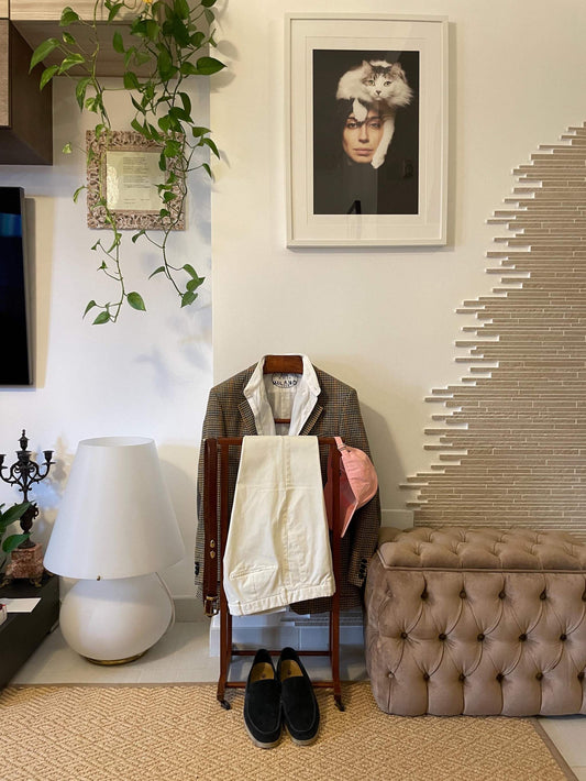 valet stand vintage in legno con abito e pantaloni appesi in ambiente elegante e retrò