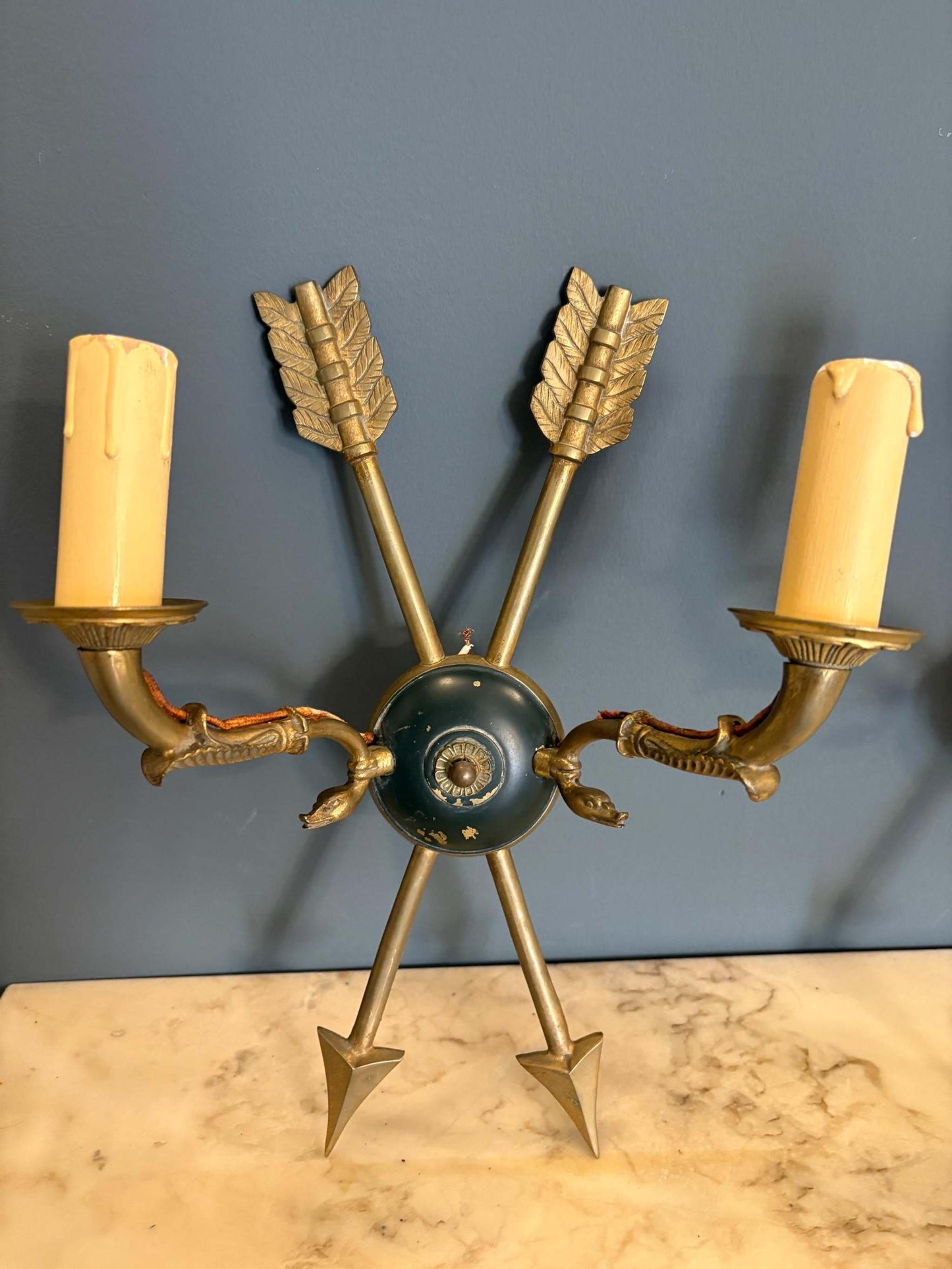 antiche appliques da parete vintage in ottone a forma di freccia con dettagli decorativi e candele su fondo grigio
