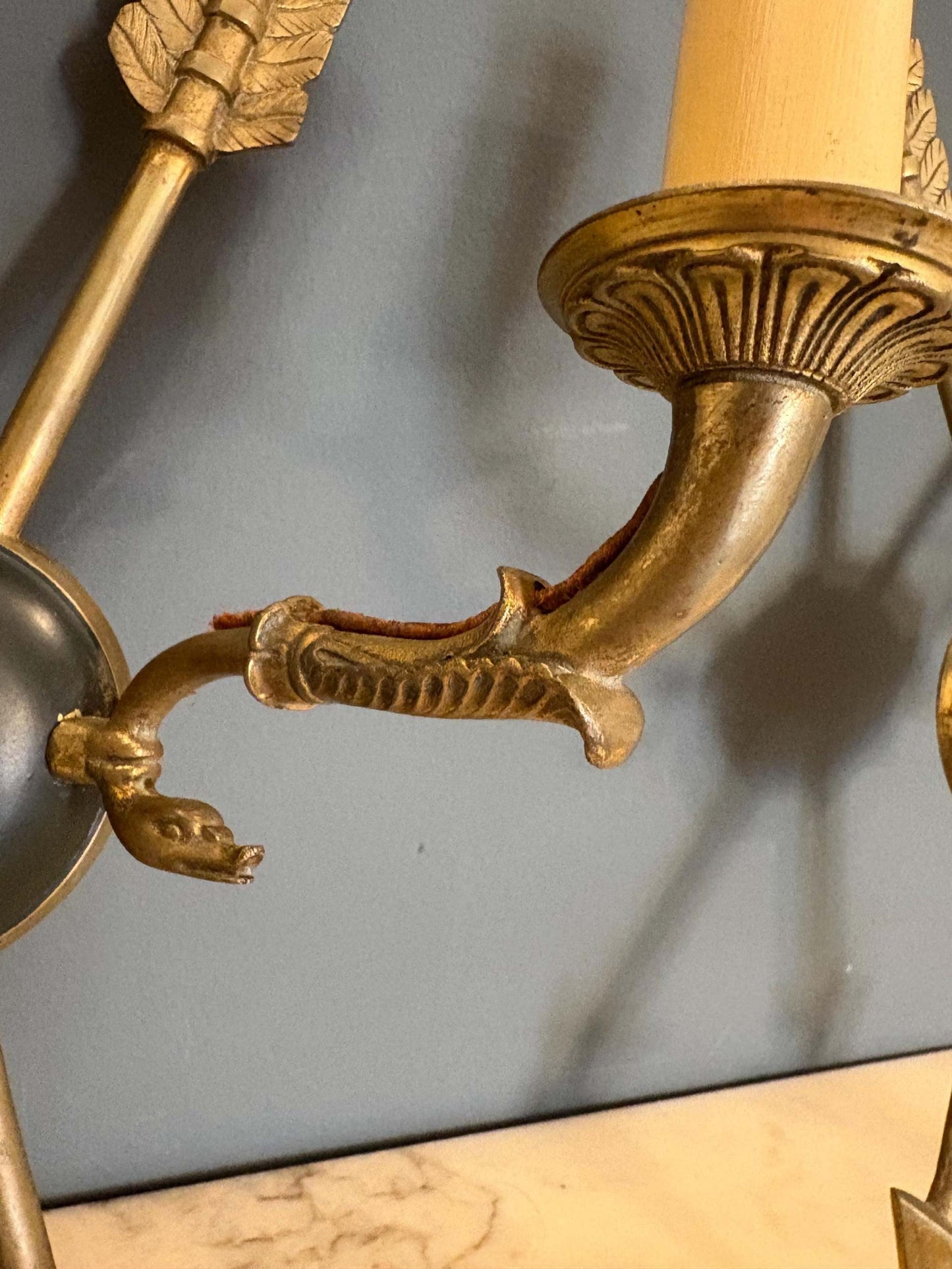 lampada da parete vintage in ottone con design a freccia e decorazioni ornate su sfondo grigio