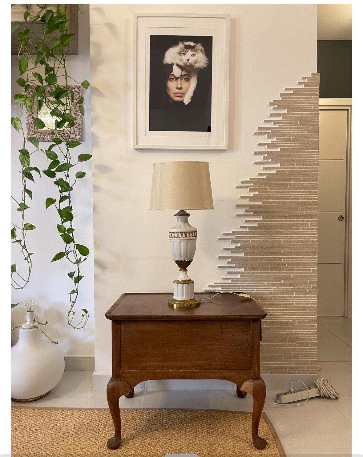 Lampada da tavolo elegante in ceramica bianca e ottone dorato stile vintage su tavolino in legno classico
