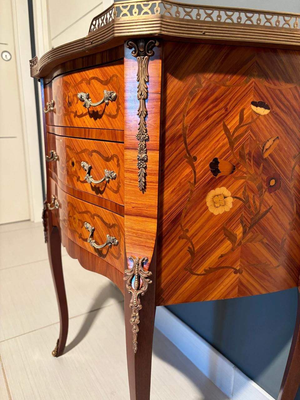 Tavolino da notte vintage francese in stile Rococò con intarsi floreali, finiture anticate e dettagli barocchi in legno pregiato.